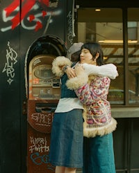 two women hugging in front of a vending machine