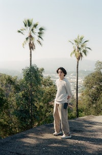 a man standing on top of a hill with palm trees in the background