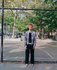 a man standing in front of a fence in a park