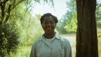 a woman with glasses standing in a wooded area